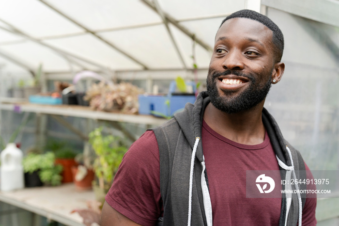 Portrait of smiling man standing in front of greenhouse