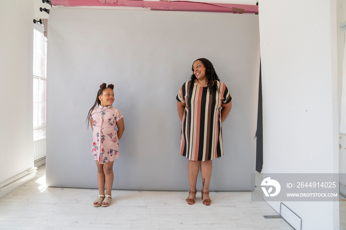 Mother and daughter (6-7) wearing dresses and looking at each other