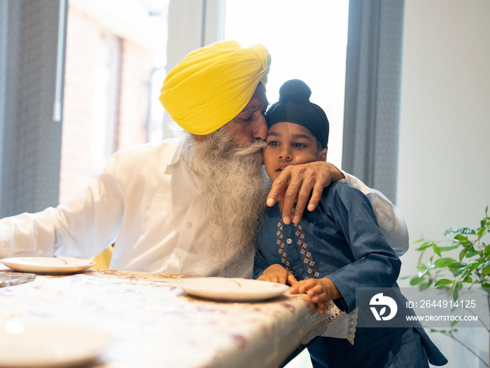 Grandfather kissing grandson (6-7) on cheek