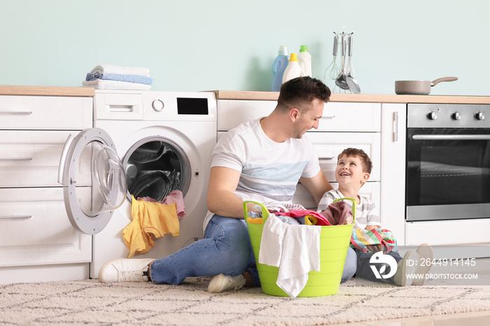 Man and his little son doing laundry at home