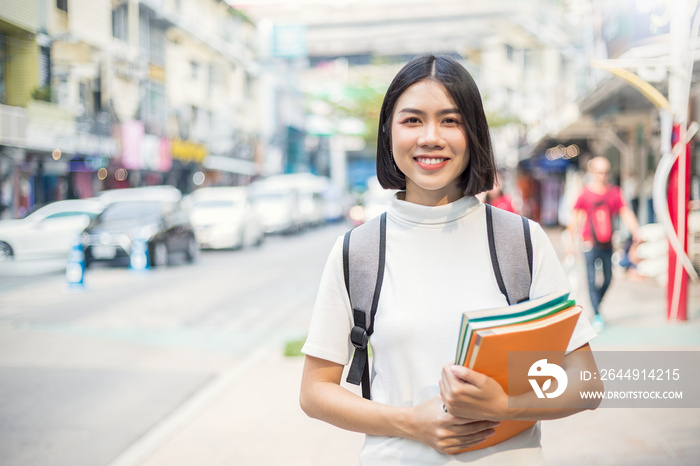 Smiling young asian woman with her book backpack in the city. Portrait of beautiful asian girl walking to school. Education tutor authentic lifestyle people back to school concept