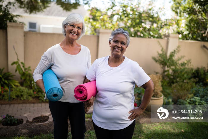 Portrait of smiling senior friends carrying exercise mats