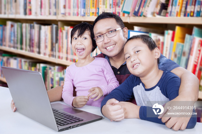 Two students and teacher with laptop in library