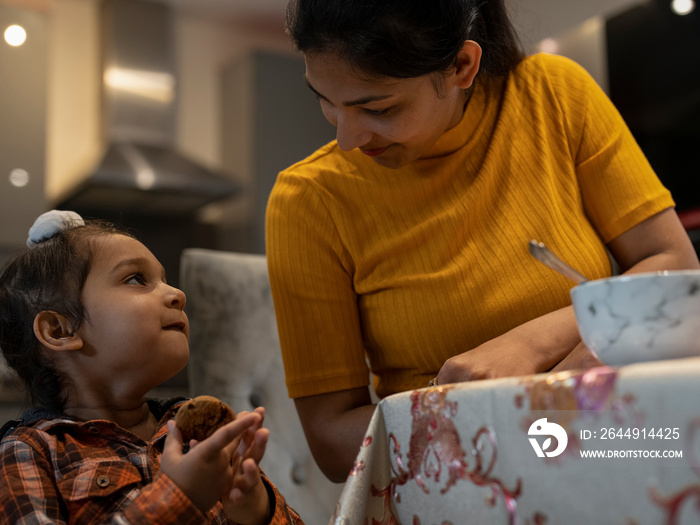 Mother and son (2-3) eating cookies at home