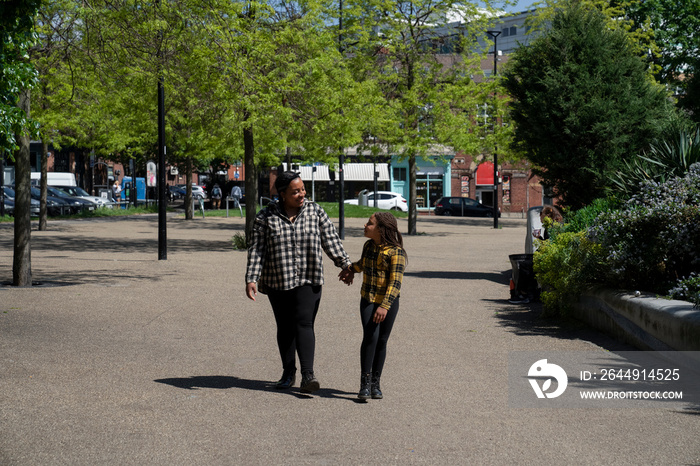 Daughter (6-7) holding mothers hand while walking in park