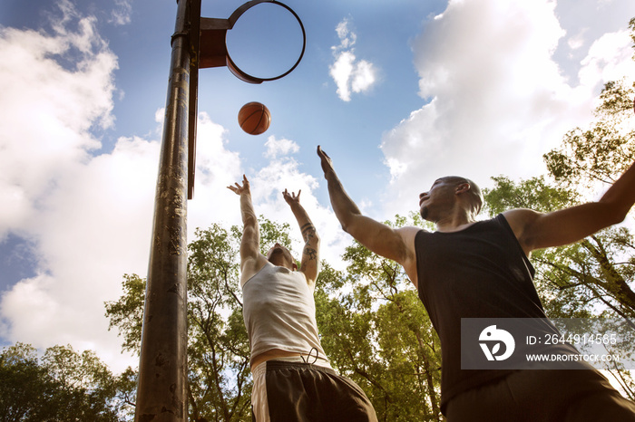 Low angle view of friends playing basketball in park