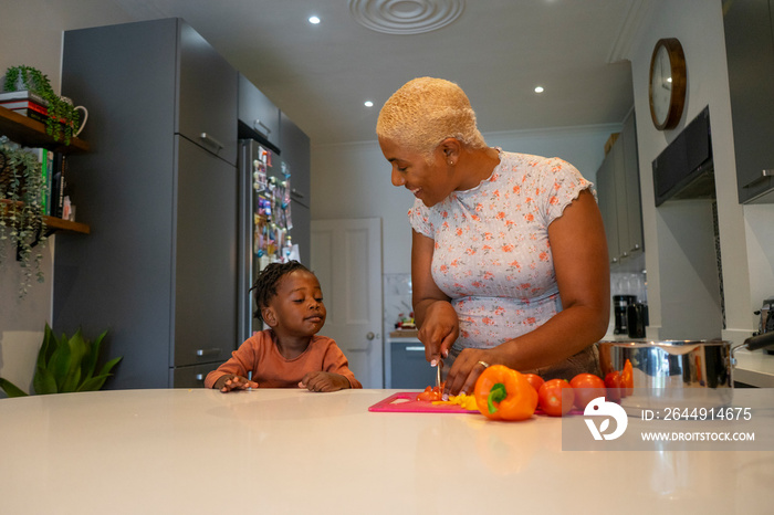 Mother and daughter (2-3) preparing food in kitchen