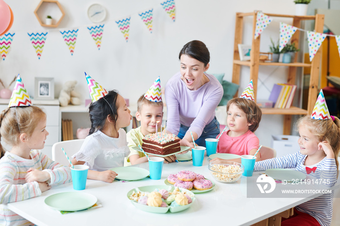 Ecstatic young woman holding birthday cake and looking at candles