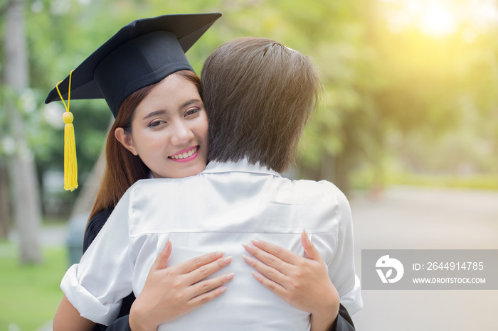 Asian female student and family hug celebrating graduation