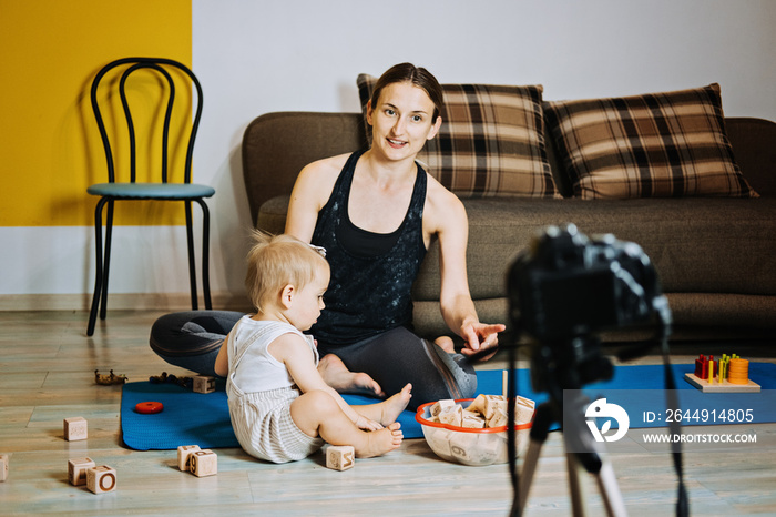 Mom blogger records video on camera with her little daughter at home.