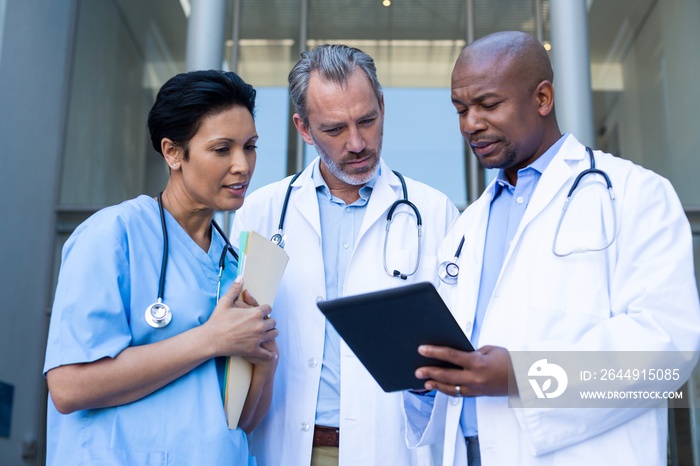 Surgeons and nurse having discussion on digital tablet