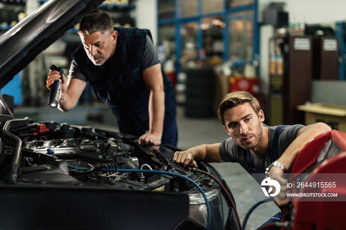 Two mechanics repairing air conditioning system in auto repair shop.