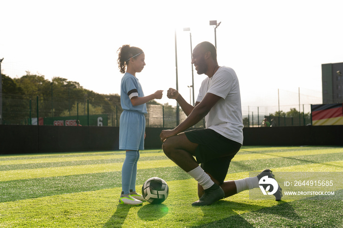 Coach and girl (6-7) on soccer field