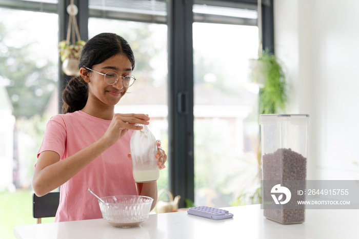 Girl eating breakfast at table in living room