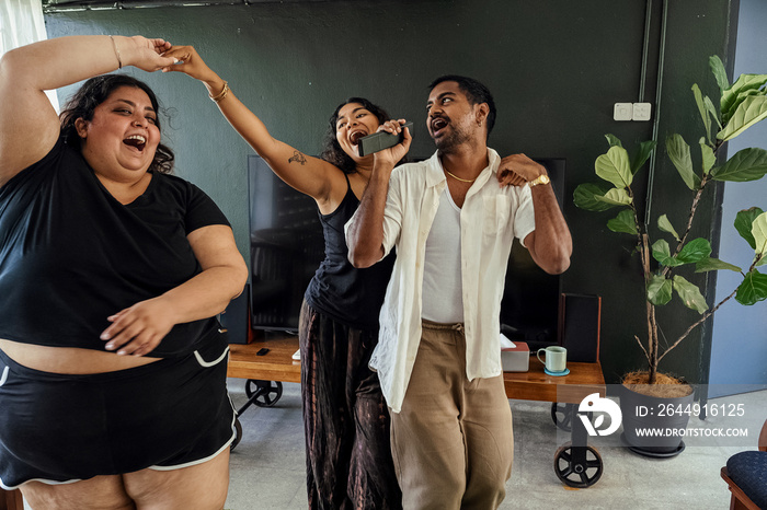 Friends dancing and singing together at home on a weekend