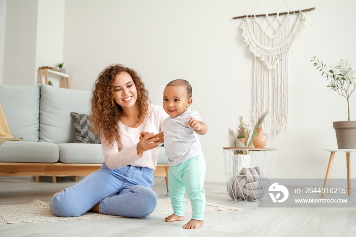 African-American mother teaching her little baby to walk at home