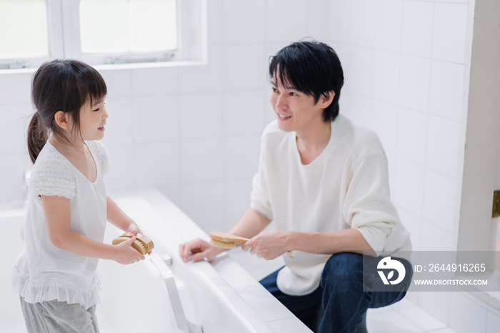 パパと一緒にお風呂掃除をする小さな女の子