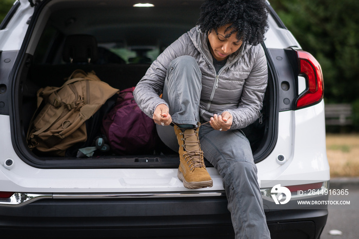 U.S. Army female soldier putting on combat boots and backpack before a hike.