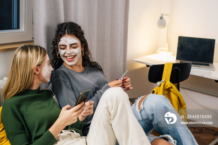 female friends with cosmetic cream mask on face enjoying time together in room