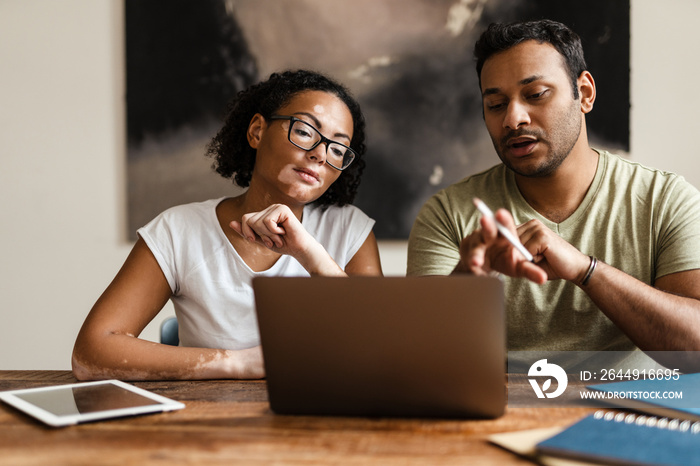 Middle eastern man and woman working with laptop together at home