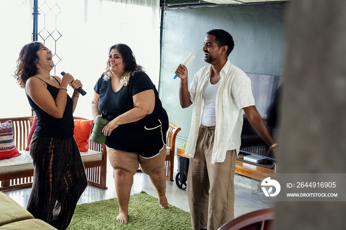 Friends dancing and singing together at home on a weekend