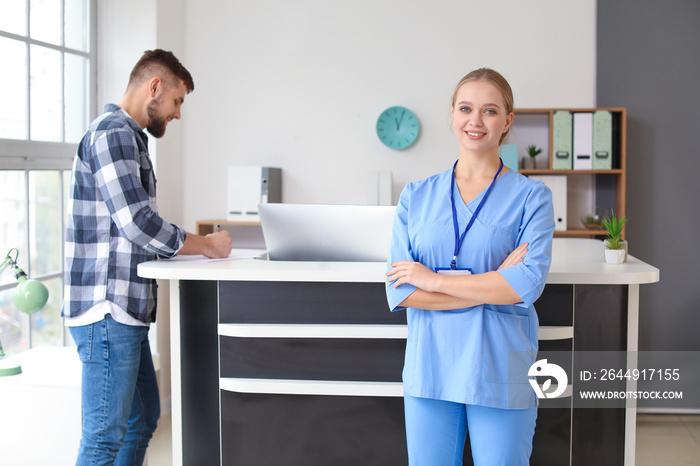 Young female receptionist near desk in clinic