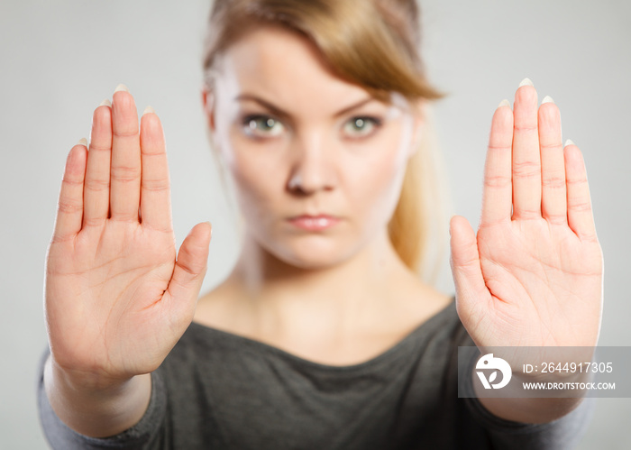 Female shows stop sign by her hand.