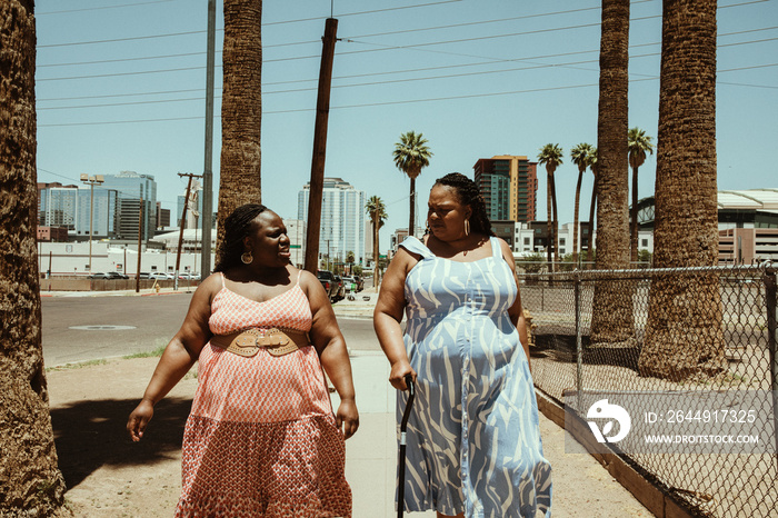 2 African American women walk away down the street talking