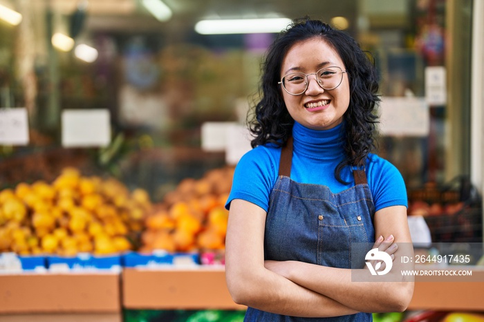 Young chinese woman employee smiling confident standing with arms crossed gesture at fruit store