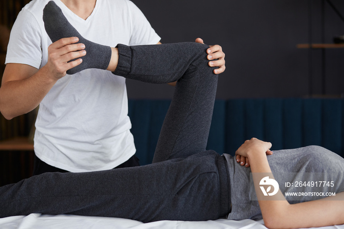 Female patient doing physical exercises with physiotherapist. Male therapist treating injured knee of young athlete.Post traumatic rehabilitation, sport physical therapy, recovery concept.