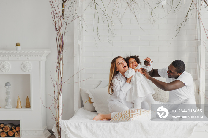 Happy interracial couple with their little daughter at home