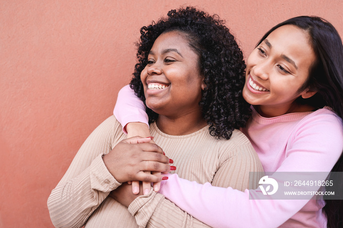 Hispanic girls laughing together and hugging each other outdoor - Focus on left woman face