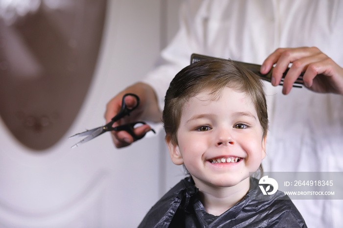 Hairdresser and boy. The boy is doing his hair. Cut hair child in the hairdresser.