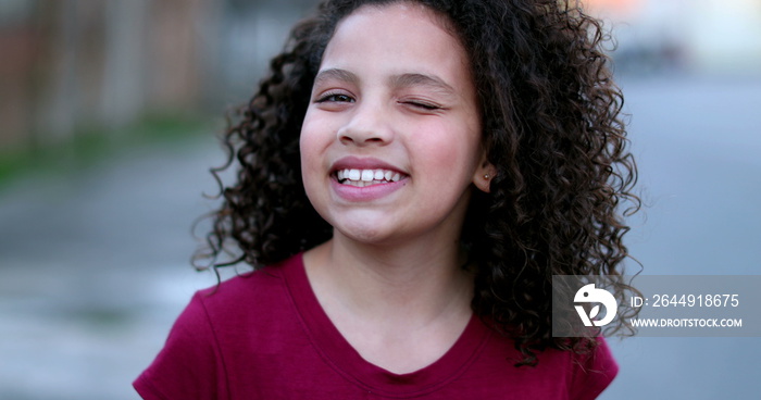 Hispanic little girl winking to camera in approval