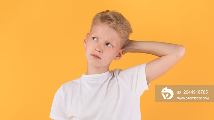 Confused puzzled male kid scratching head at studio