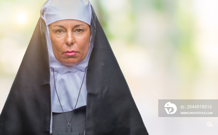 Middle age senior christian catholic nun woman over isolated background with serious expression on face. Simple and natural looking at the camera.