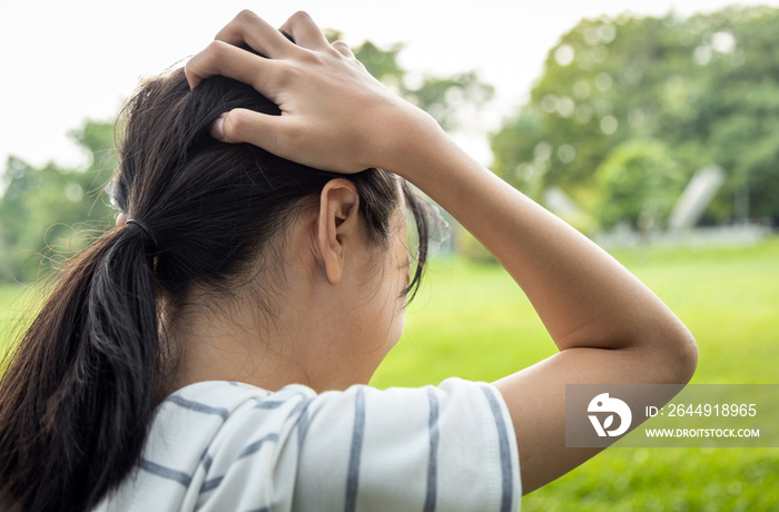 Sick asian child girl holding her painful head, brain cancer,hemorrhagic stroke and tumor inside brain,female teenage person with a severe headache in outdoor park,health problem , health care concept