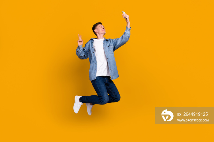 Full size profile side photo of young man jump up shooting selfie mobile isolated over yellow color background