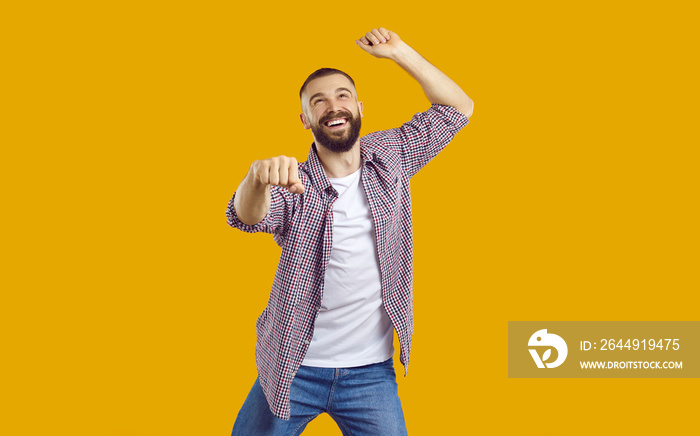 Let’s have a party. Happy man dancing isolated on an orange yellow color background. Studio portrait of a cheerful, excited guy in casual clothes dancing gangnam style and smiling