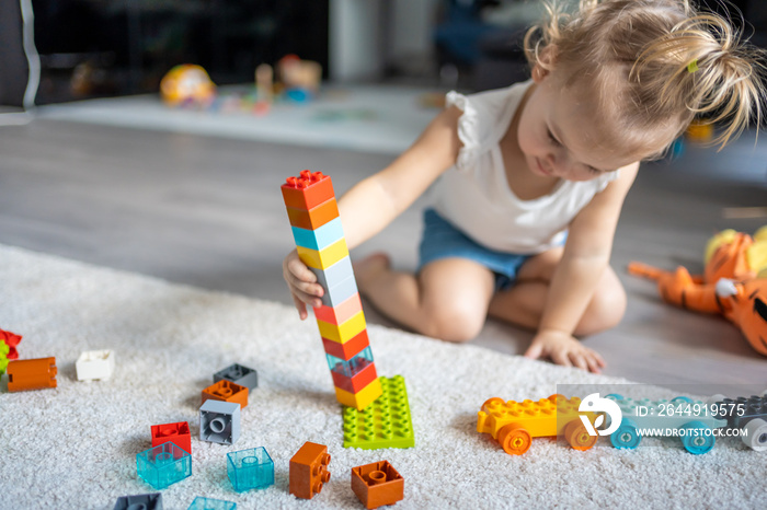 Caucasian child a little girl is playing in the constructor at home. Educational toys for children.