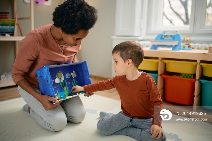 Small boy enjoys while playing with his African American kindergarten teacher.