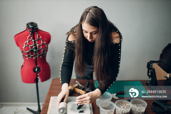 Tanner woman making leather harness belt goods on workshop. Working process of leather craftsman.