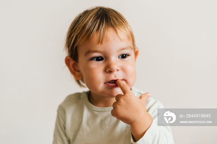 Toddler with finger in her mouth. Teething snore gums concept. Sucking finger