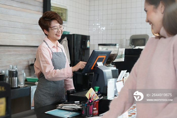 young woman wears eyeglasses smile happily while working in coffee shop, asian female cashier taking order coffee and bakery from the waitress