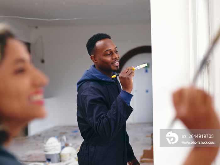 Smiling couple painting house walls