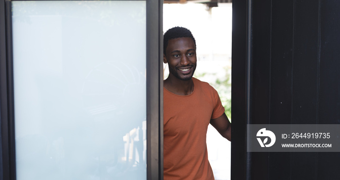 Happy african american man walking through door and smiling