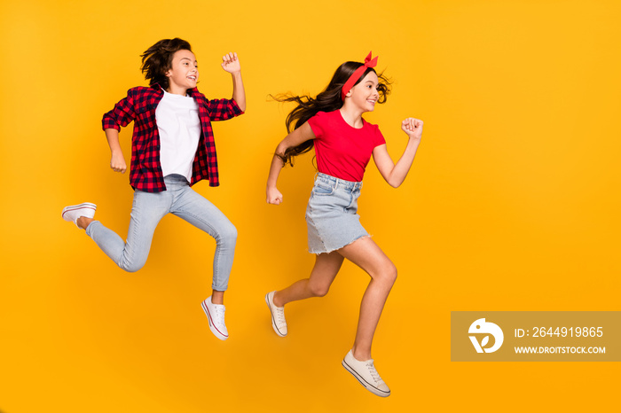 Full body profile photo of small carefree kids running jumping have fun toothy smile isolated on yellow color background