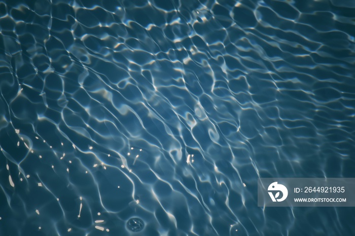 Defocus blurred transparent blue colored clear calm water surface texture with splashes and bubbles. Trendy abstract nature background. Water waves in sunlight with copy space. Blue water shine