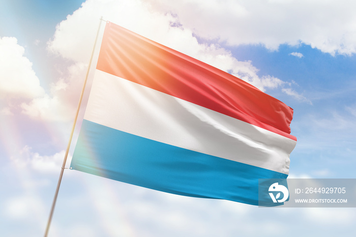 Sunny blue sky and a flagpole with the flag of luxembourg