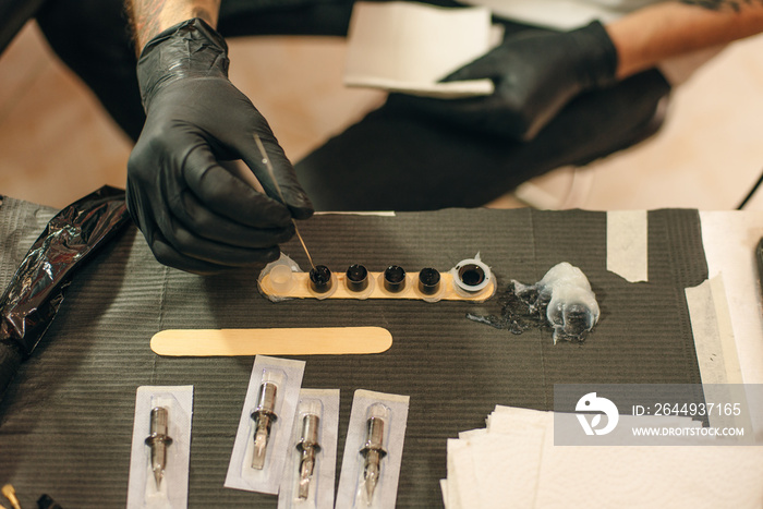 Tattoo artist workplace with machine and bottles with black tattoo ink